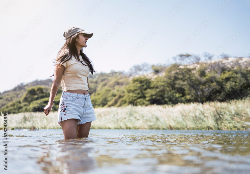 Beautiful young latin woman bathes in a lake enjoying a summer day.