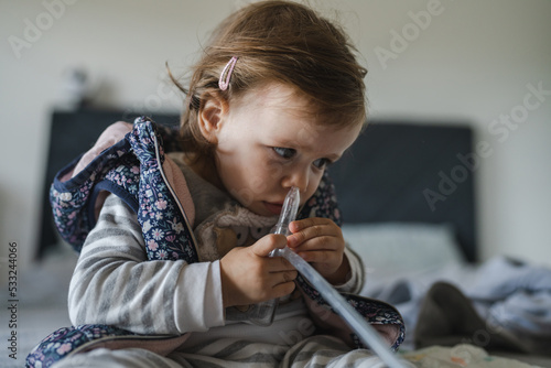 One girl child toddler use nose snot sucker nasal aspirator clean nose photo
