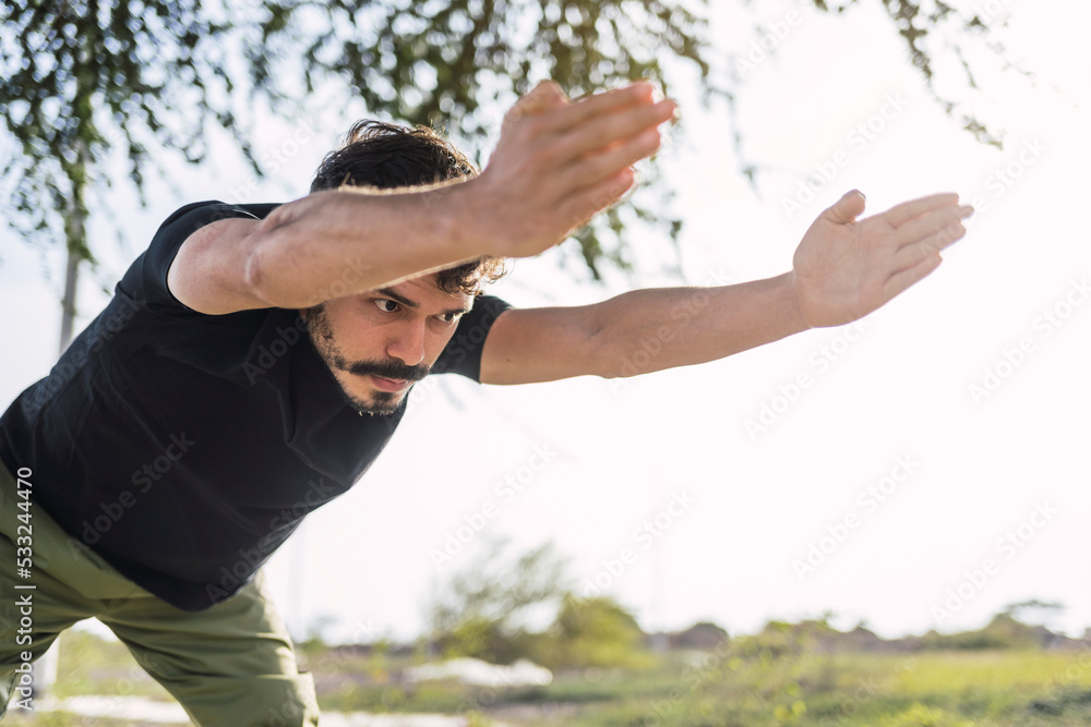 Getting ready to do his best. Portrait of a sporty young man stretching his arms while exercising outdoors. Getting ready to do his best. Portrait of a sporty young man stretching his arms while exercising outdoors.