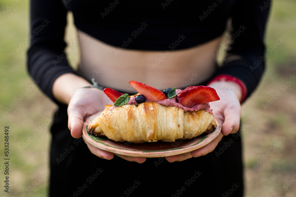 mujer con croissant de frutos rojos 
