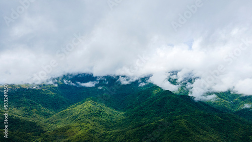 Bird's-eye view of a green mountain full of trees and misty mountains beautiful, fresh atmosphere.