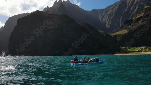 Romantic couple relaxing on a canoe in the water of the Pacific Ocean near the coast of Na Pali, Kauai, Hawaii photo