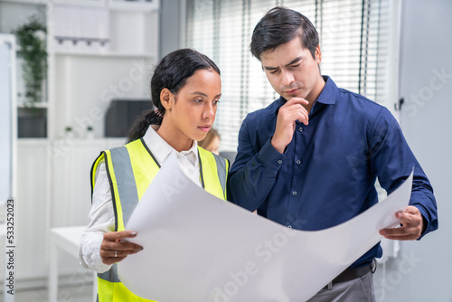 Competent investor investor discuss and brainstorm with engineer on blueprints, construction plans before putting them into action. Professional establishing investment plan for engineering projects. photo