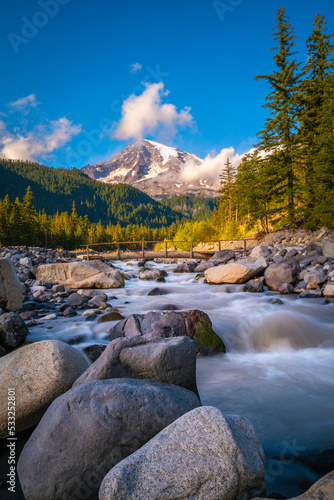 Mount Rainier, spruce forest, glacial rocks, and the Nisqually River in Mt Rainier National Park in Washington State. Majestic tranquil autumn landscape of the Cascade Mountains in North America. 