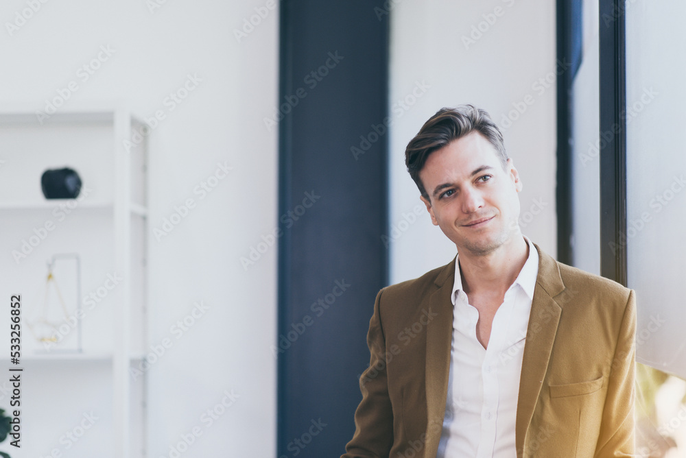 Smart businessman smiling face and standing near window at office Smart businessman smiling face and standing near window at office