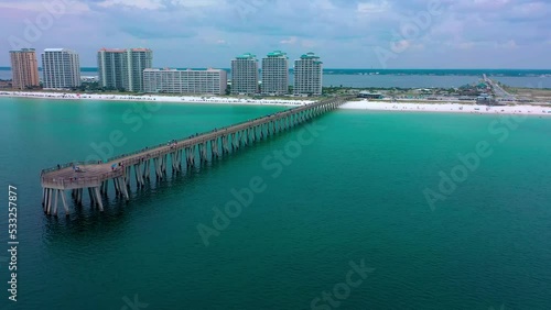 Aerial drone panning left view of the Navarre Beach Florida Pier with some dark clouds in the background.