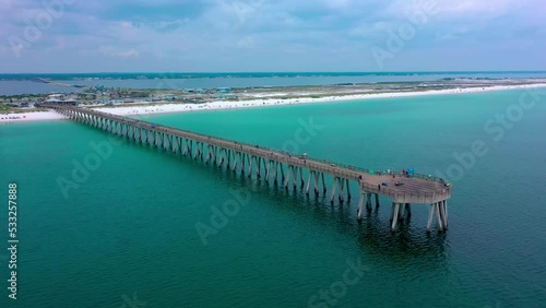 Aerial drone panning right view of the Navarre Beach Florida Pier with some dark clouds and the white sand beach in the background. photo