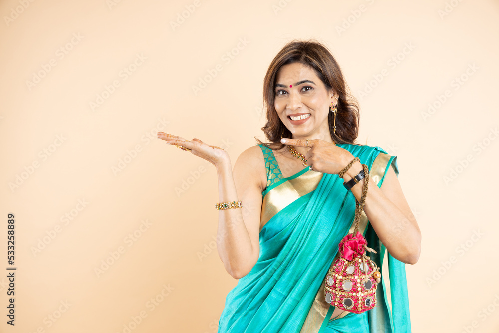 Happy young Indian woman wearing saree shows blank space for your