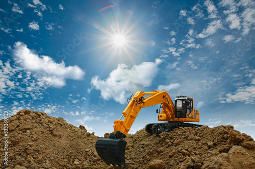 Excavator with Bucket are digging soil in the construction site on the blue sky and sunbeam background