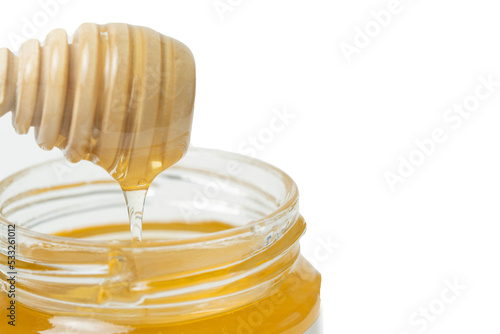 Honey drips from a wooden honey dipper on a yellow background. Sweet bee product for your design with copyspace. Close-up