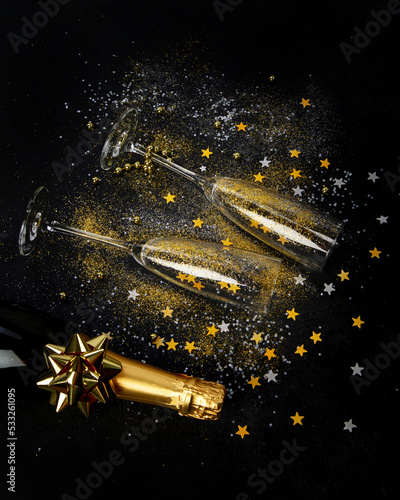 Glass of champagne and bottle on dark background.