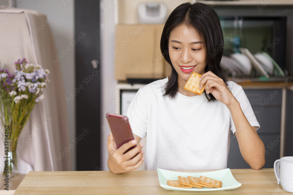 Cozy lifestyle concept, Young woman eating crackers and surf social media on smartphone at home Cozy lifestyle concept, Young woman eating crackers and surf social media on smartphone at home