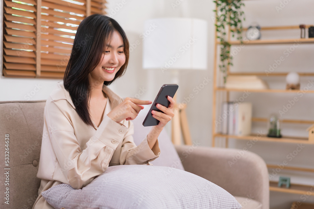 Lifestyle at home concept, Asian woman use smartphone to surfing social media while sitting on sofa Lifestyle at home concept, Asian woman use smartphone to surfing social media while sitting on sofa