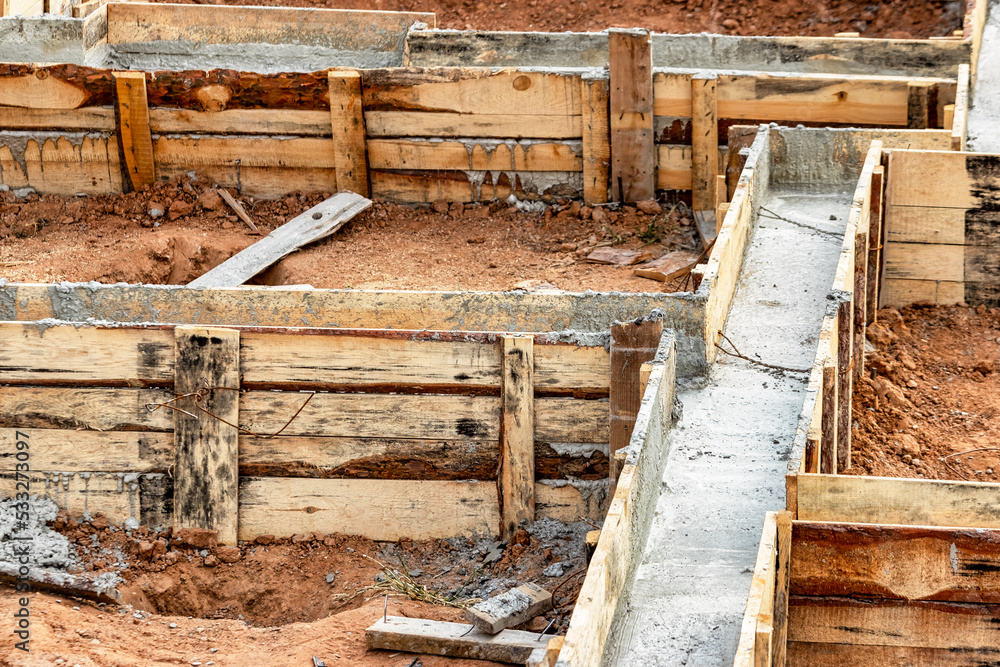 Reinforced concrete foundation of a modern monolithic residential building. Prepared formwork with reinforcing mesh for pouring concrete. Dirt and clay at the construction site.