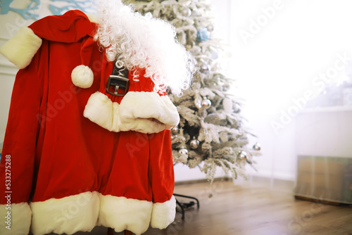 Santa costume hanging in white room. Chair with clothes from Santa Claus © alexkich