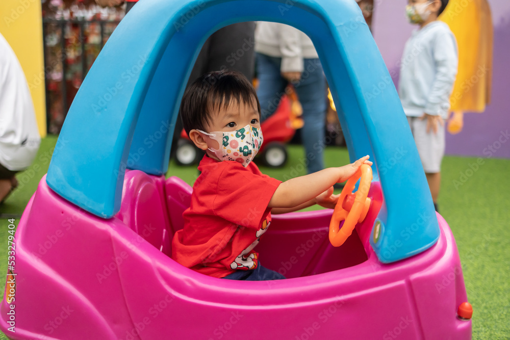 Happy 1-2 years old child enjoying playing car on playground Happy 1-2 years old child enjoying playing car on playground