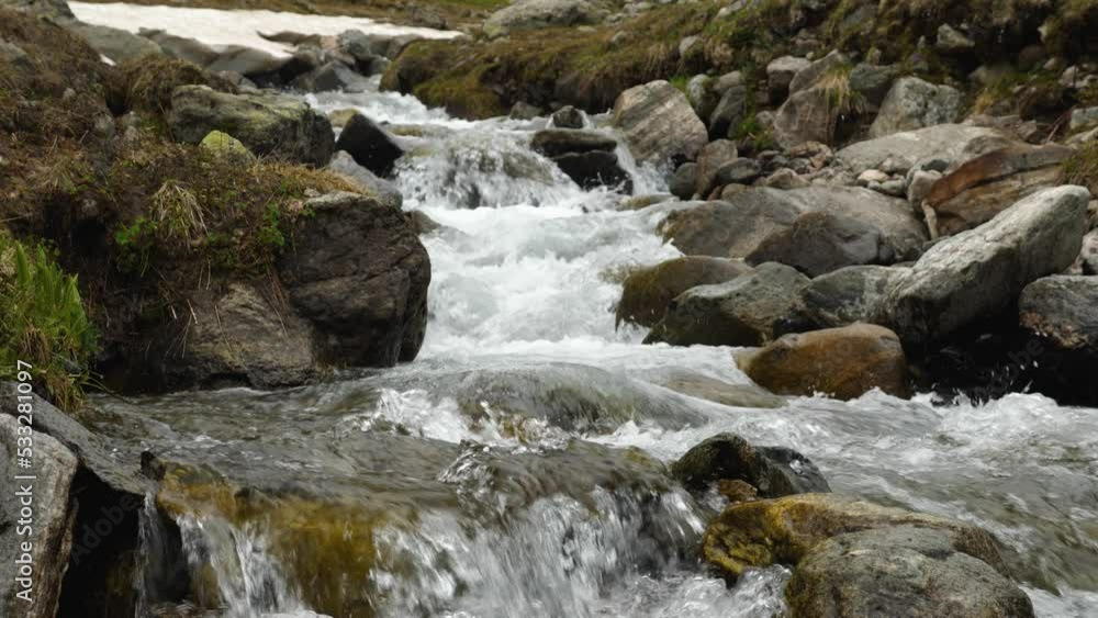 Slow motion shot of clear mountain water flowing down a rocky bed. The stream of water making waves and foam. The beauty of wildlife Slow motion shot of clear mountain water flowing down a rocky bed. The stream of water making waves and foam. The beauty of wildlife