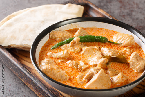 Chicken curry with coconut milk and sri lanka spices in a bowl on a wooden tray. Horizontal