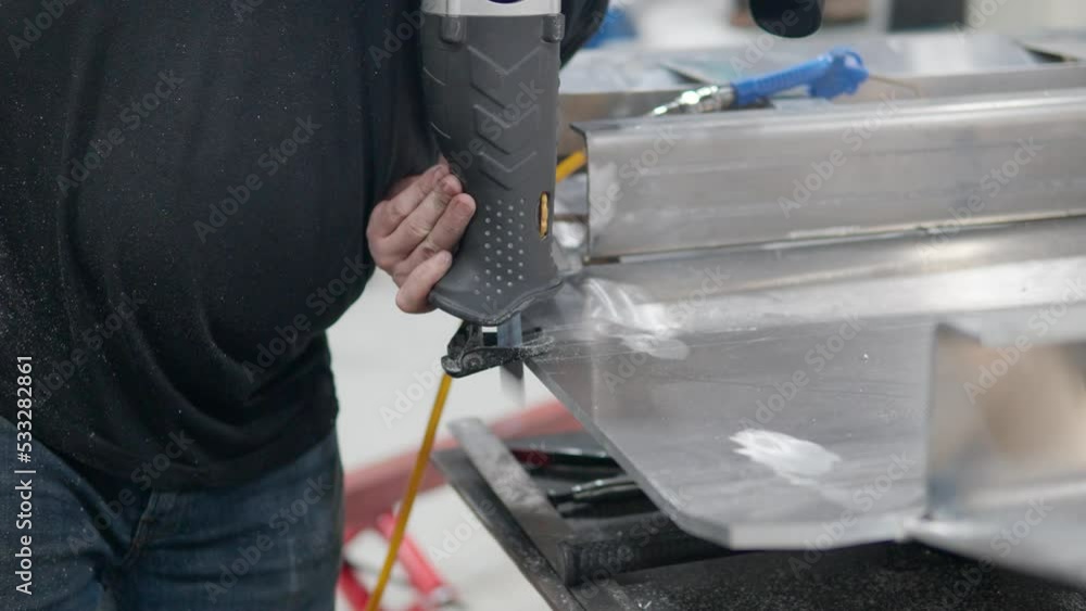 Worker's Hands Using Reciprocating Saw Cutting Thick Aluminum Plate - close-up Worker's Hands Using Reciprocating Saw Cutting Thick Aluminum Plate - close-up