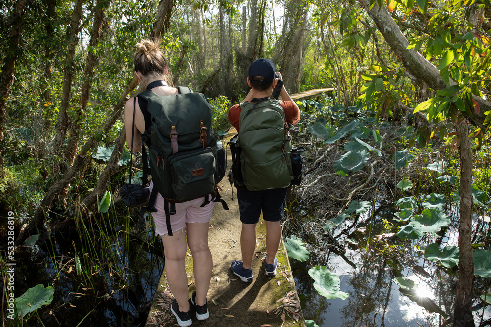 Young Male and female photographer from back view enjoying hiking in a tropical forest taking photos of landscape. Young Male and female photographer from back view enjoying hiking in a tropical forest taking photos of landscape.