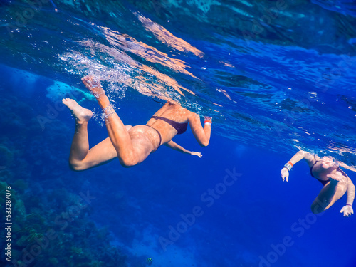 two young girls in black bikini swimming in clear blue water