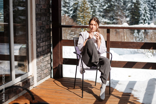 Woman sitting on terrace with coffee during winter morning