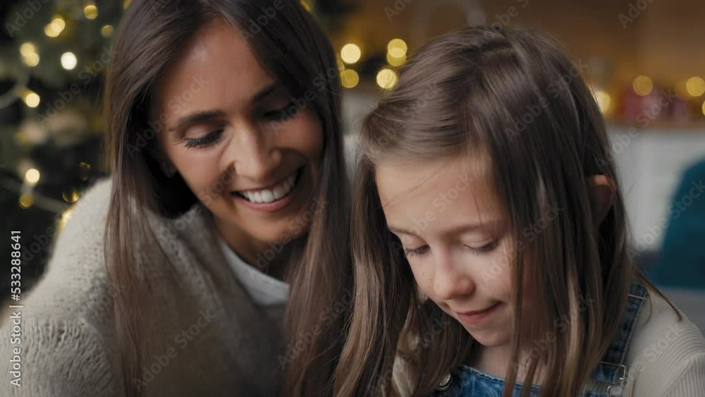 Tilt down of happy caucasian mother and daughter packing Christmas gifts together on floor. Shot with RED helium camera in 8K. Tilt down of happy caucasian mother and daughter packing Christmas gifts together on floor. Shot with RED helium camera in 8K.