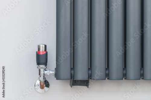 Thermostatic radiator valve on modern Graphite radiatior. Grey Wall background.
