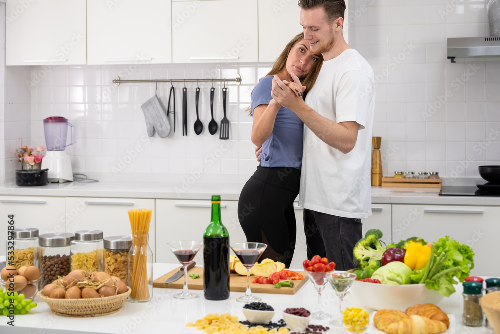 Happy couple spending time together, cooking romantic dinner and dancing in kitchen. Healthy eating at home .
