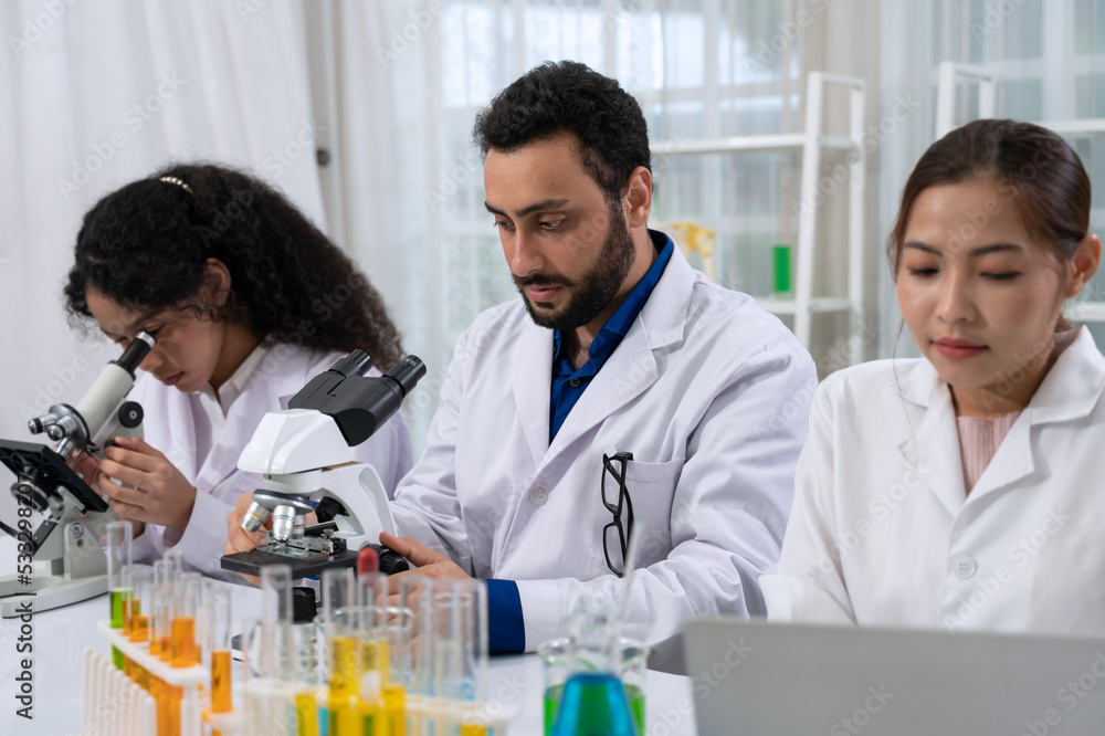 Scientist team in white laboratory coat working with microscope and laptop for research in scientific research laboratory . Scientist team in white laboratory coat working with microscope and laptop for research in scientific research laboratory .
