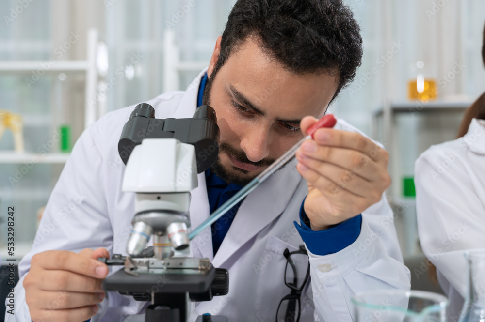 Male scientist dropping chemical liquid on slide at microscope. Science and Technology concept. Male scientist dropping chemical liquid on slide at microscope. Science and Technology concept.