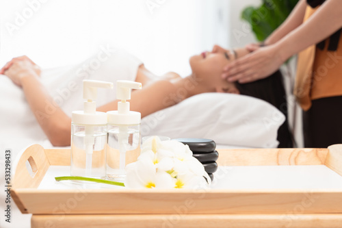 Face massage. Young woman in spa environment. Blurred face  focused on essential oil bottle..