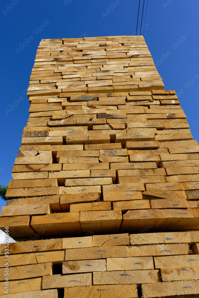 Blocks of pine sawn timber for the construction of roof houses and cottages stacked on the lumberyards site, ready for sale