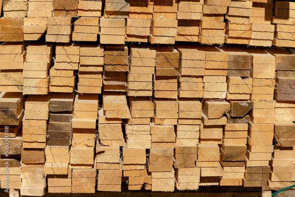 Blocks of pine sawn timber for the construction of roof houses and cottages stacked on the lumberyards site, ready for sale Blocks of pine sawn timber for the construction of roof houses and cottages stacked on the lumberyards site, ready for sale