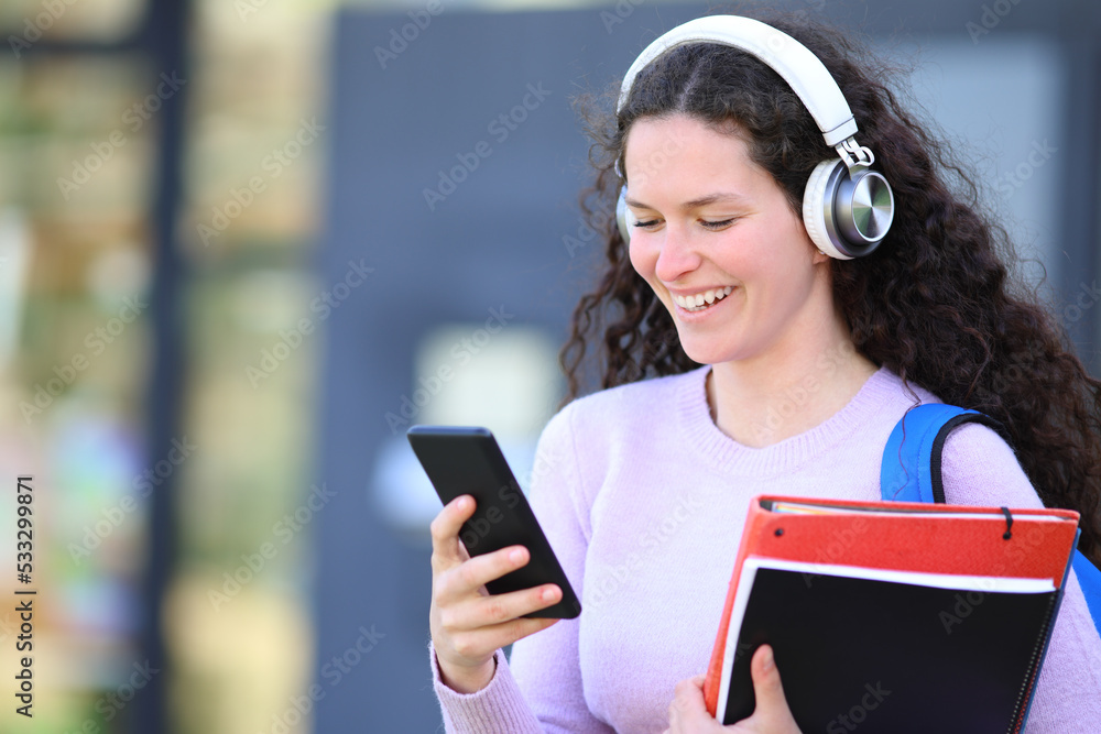 Happy student walks listening audio on phone