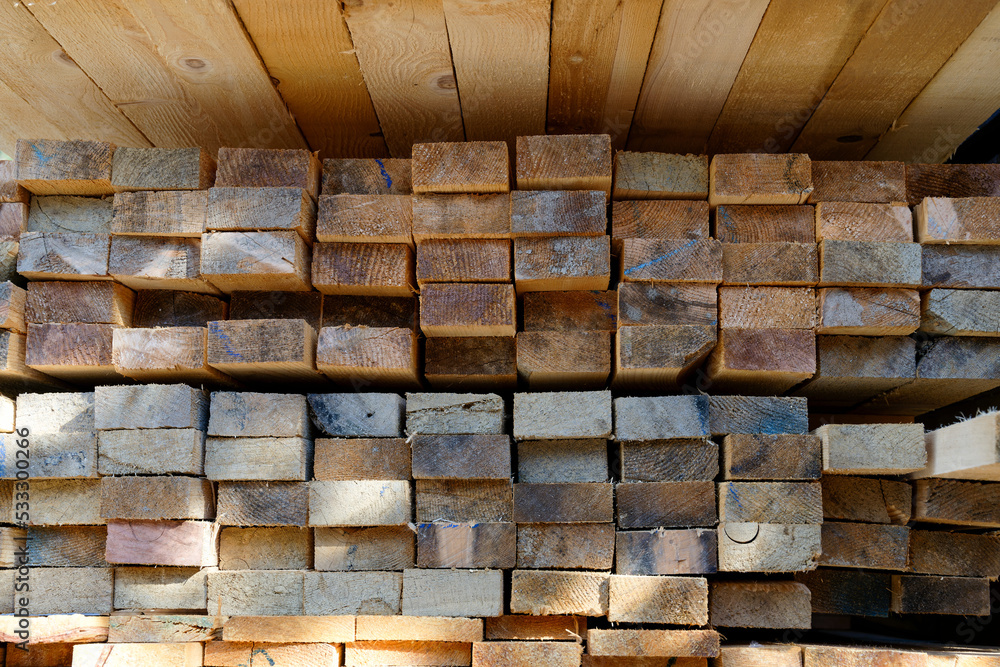 Blocks of pine sawn timber for the construction of roof houses and cottages stacked on the lumberyards site, ready for sale Blocks of pine sawn timber for the construction of roof houses and cottages stacked on the lumberyards site, ready for sale