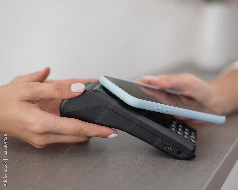 A woman pays using a non -contact payment of the NFC used by a smartphone. A woman pays using a non -contact payment of the NFC used by a smartphone.
