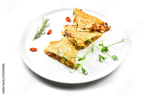 Quesadilla with cheese and vegetables in a white plate. Close-up, selective focus. White background.