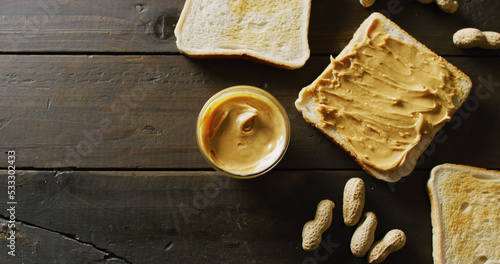 Image of close up of toasts with peanut butter on wooden background