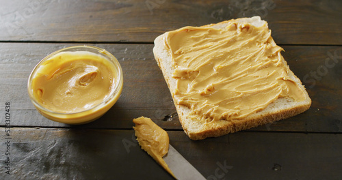Image of close up of toast with peanut butter on wooden background