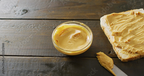 Image of close up of toast with peanut butter on wooden background