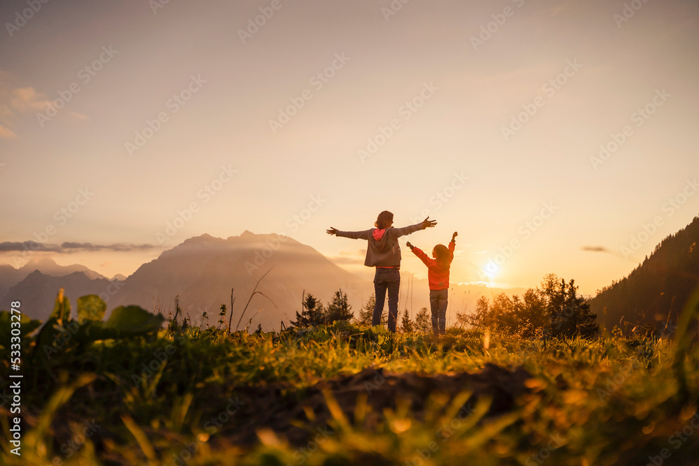 Girl and woman standing with arms outstretched on top of mountain Stock ...