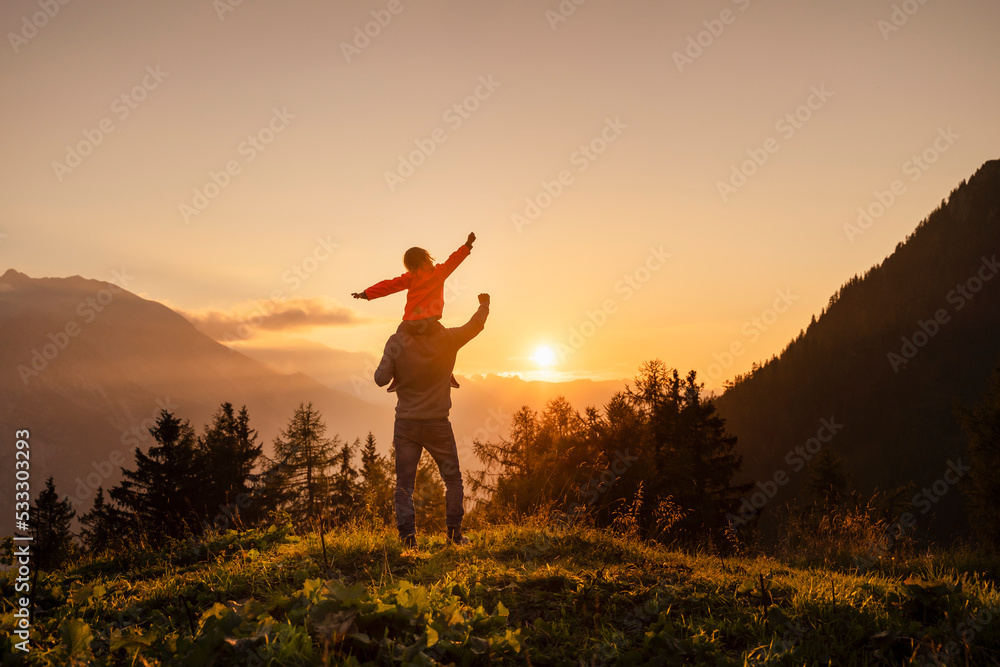 Man carrying daughter with raising fist on shoulder at mountain Man carrying daughter with raising fist on shoulder at mountain