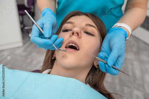 woman dentist performs a professional examination of the oral cavity in a beautiful woman.