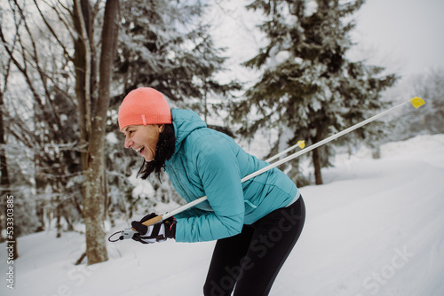 Senior woman skiing in the middle of snowy forest.