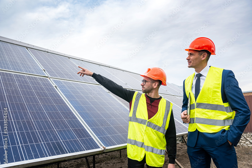 the director of company inspects the work of an employee in clothing installed solar panels. the director of company inspects the work of an employee in clothing installed solar panels.