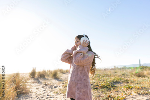 Girl wearing ear muffs at beach on sunny day photo