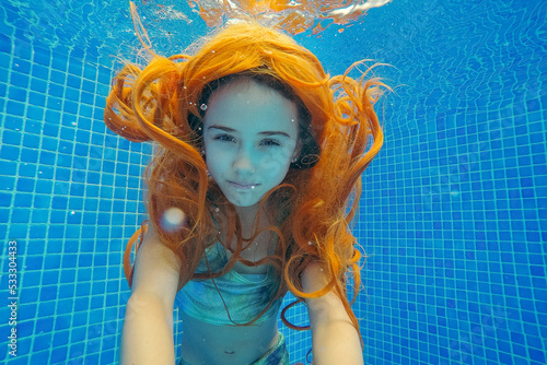 Redhead girl in swimwear swimming underwater photo