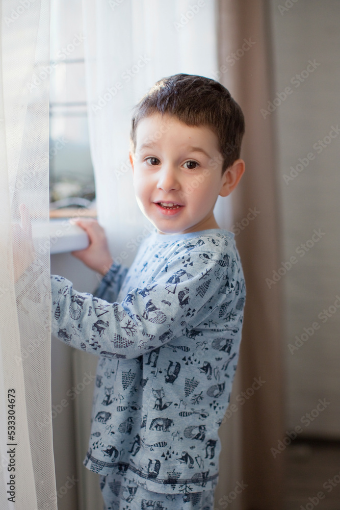 Cute boy standing by window at home Cute boy standing by window at home