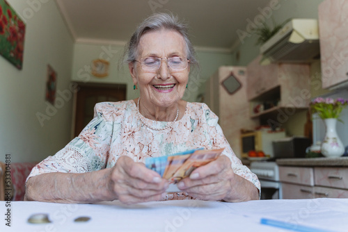 Happy senior woman counting paper currency at home photo